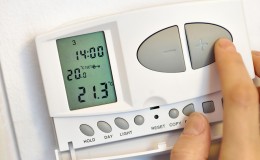 hand pressing button on digital thermostat
